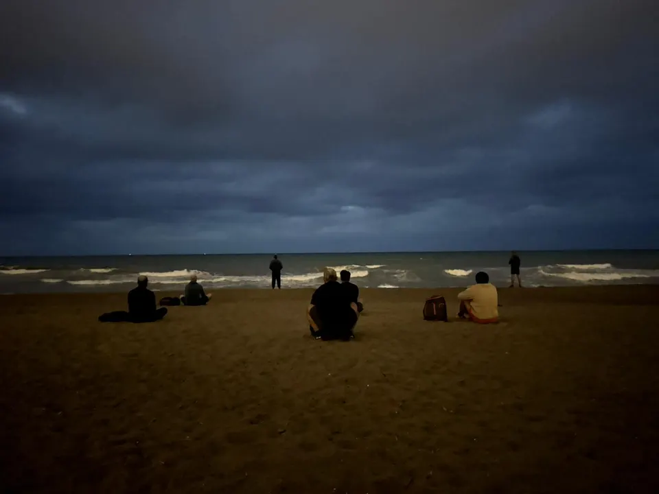 The men facing the sea in silence after training